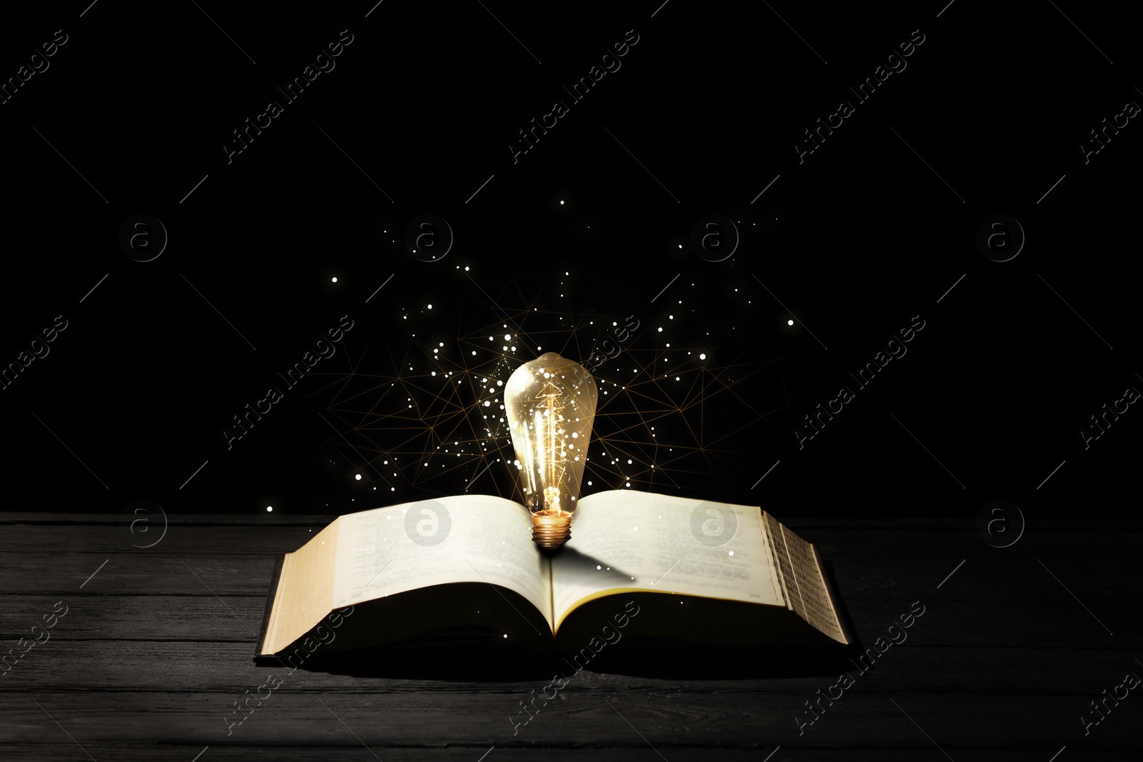 Image of Book with glowing light bulb on wooden table and magic lights