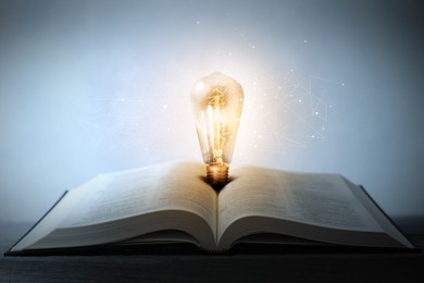 Image of Book with glowing light bulb on wooden table