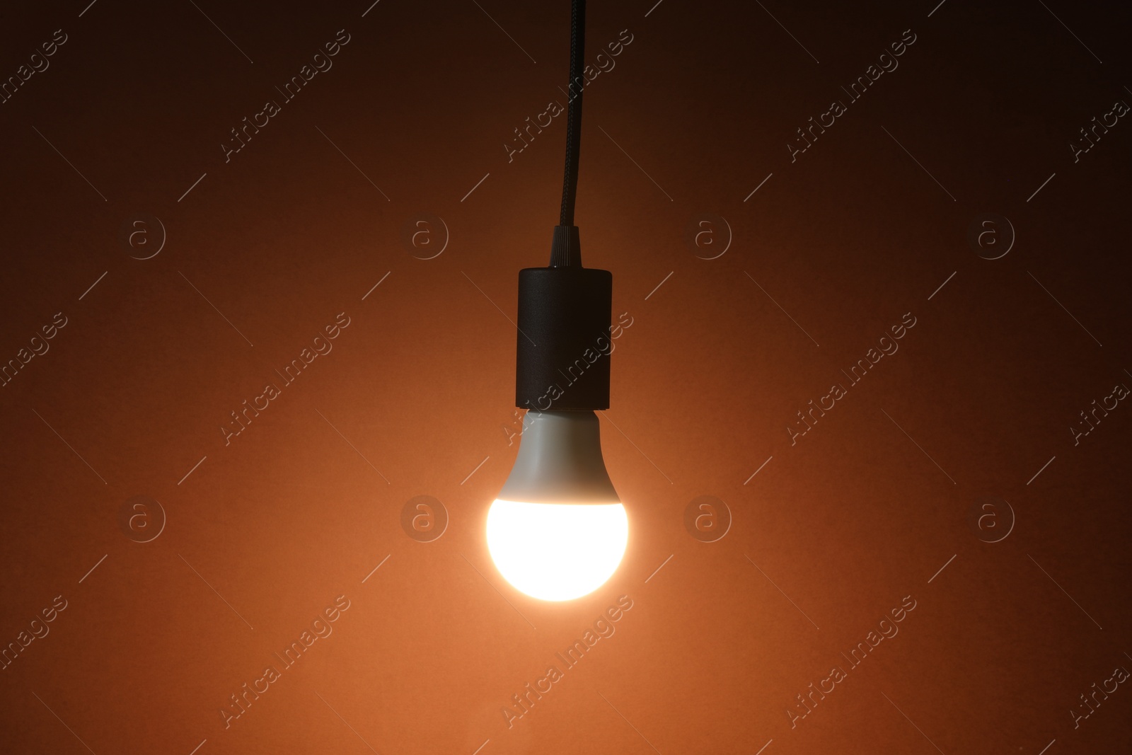 Photo of Glowing light bulb hanging on color background