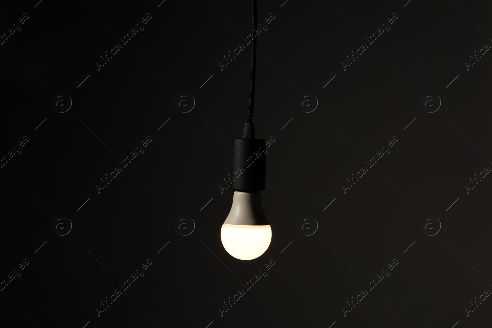 Photo of Glowing light bulb hanging on dark background