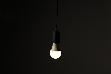 Photo of Glowing light bulb hanging on dark background