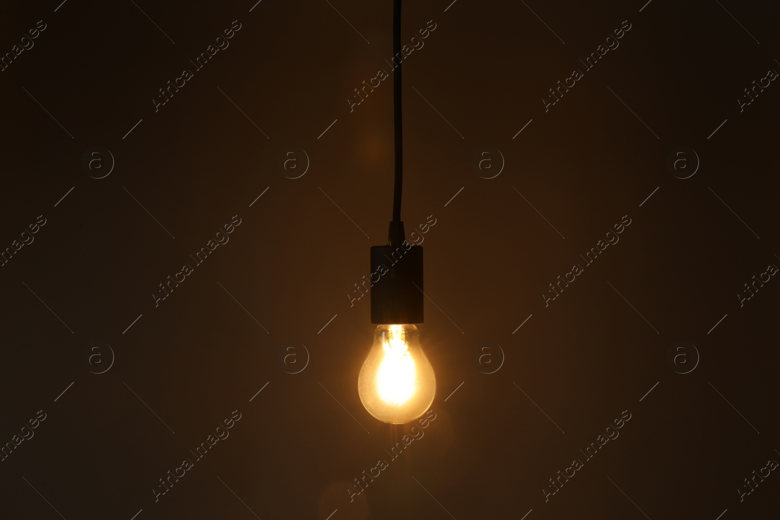 Photo of Glowing light bulb hanging on dark background