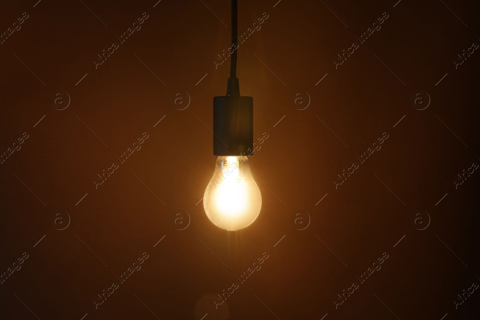 Photo of Glowing light bulb hanging on dark background