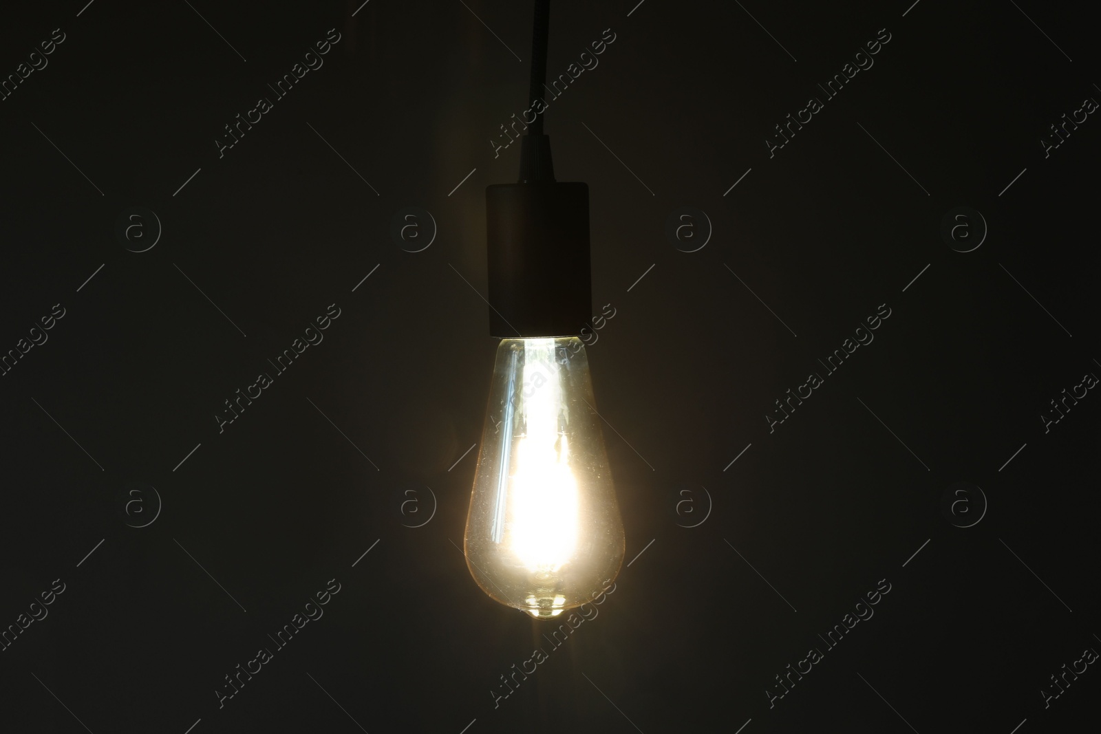 Photo of Glowing light bulb hanging on dark background