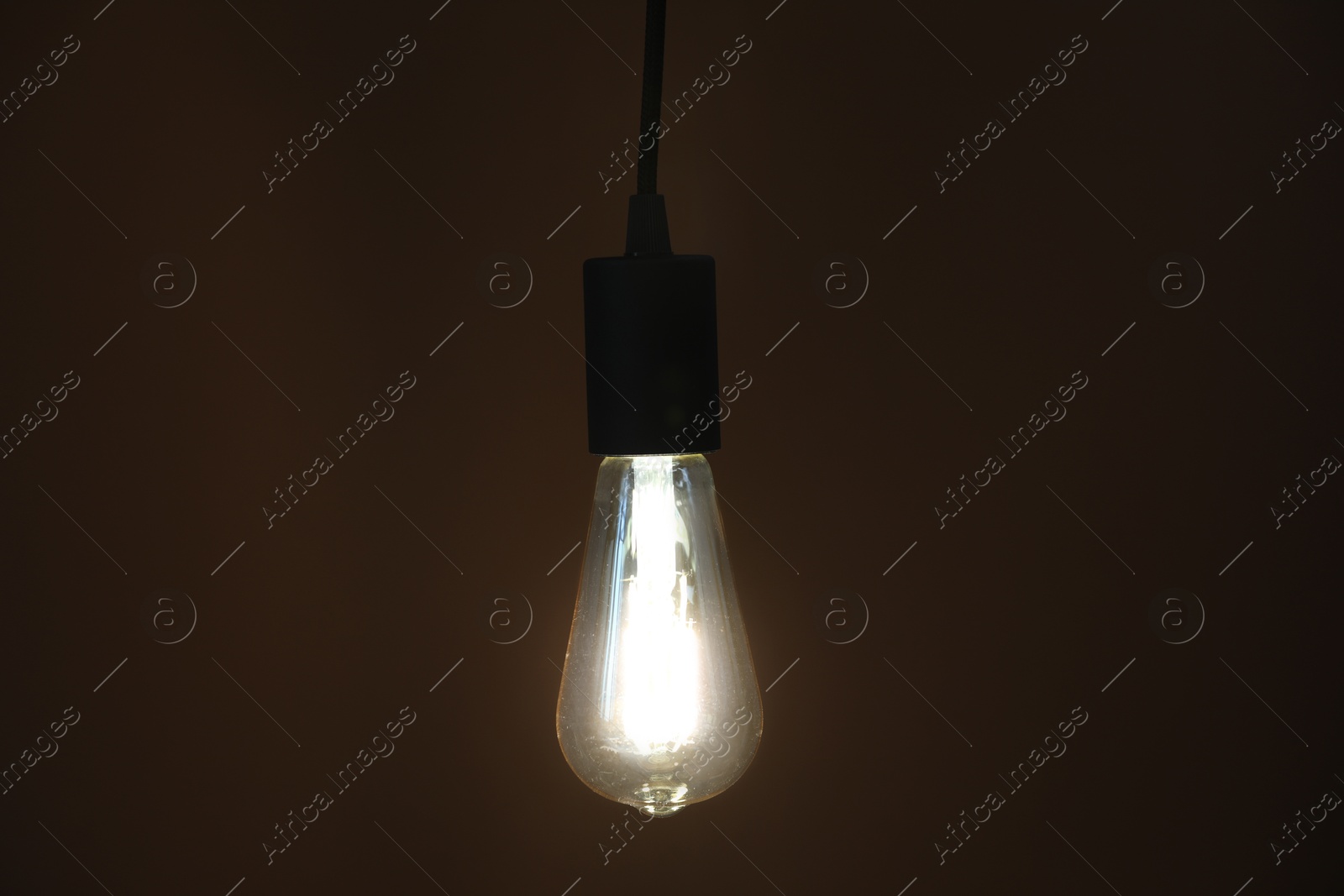 Photo of Glowing light bulb hanging on dark background