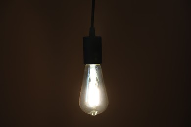 Photo of Glowing light bulb hanging on dark background