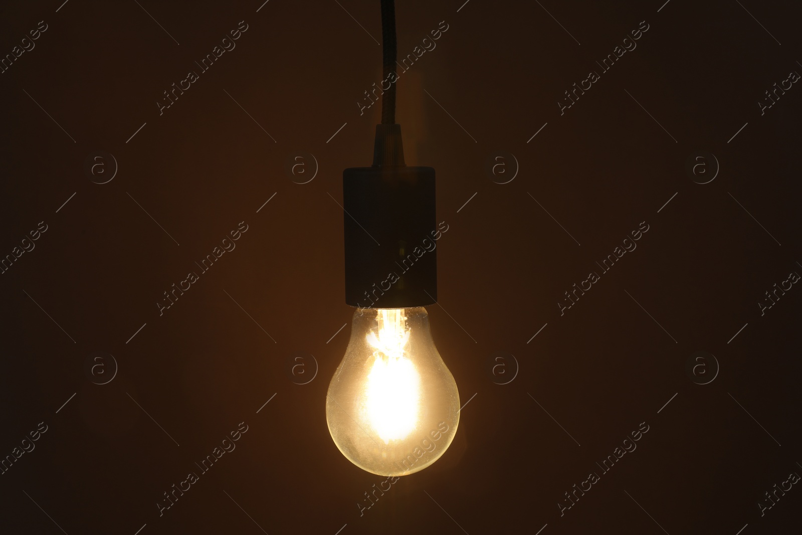 Photo of Glowing light bulb hanging on dark background