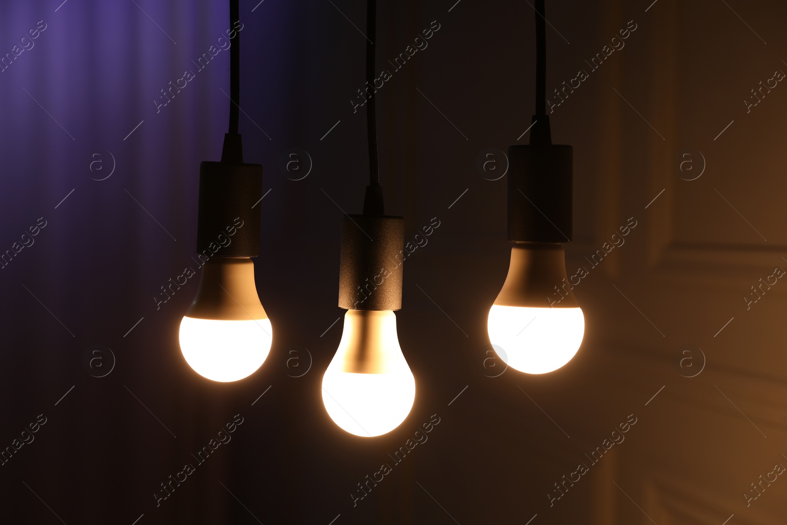 Photo of Glowing light bulbs hanging near wall, closeup