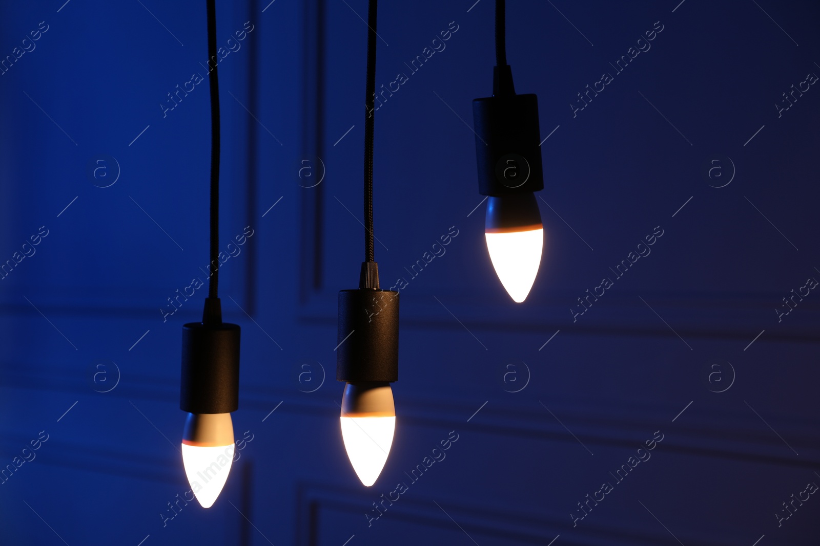 Photo of Glowing light bulbs hanging near wall indoors