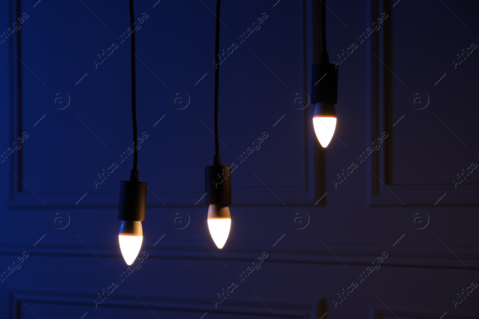 Photo of Glowing light bulbs hanging near wall indoors