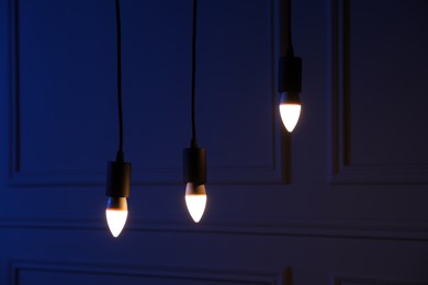 Photo of Glowing light bulbs hanging near wall indoors