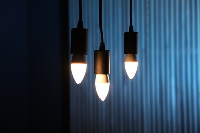 Photo of Glowing light bulbs hanging against color background