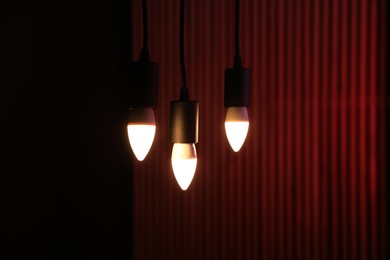 Photo of Glowing light bulbs hanging against color background