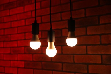 Photo of Glowing light bulbs hanging against brick wall