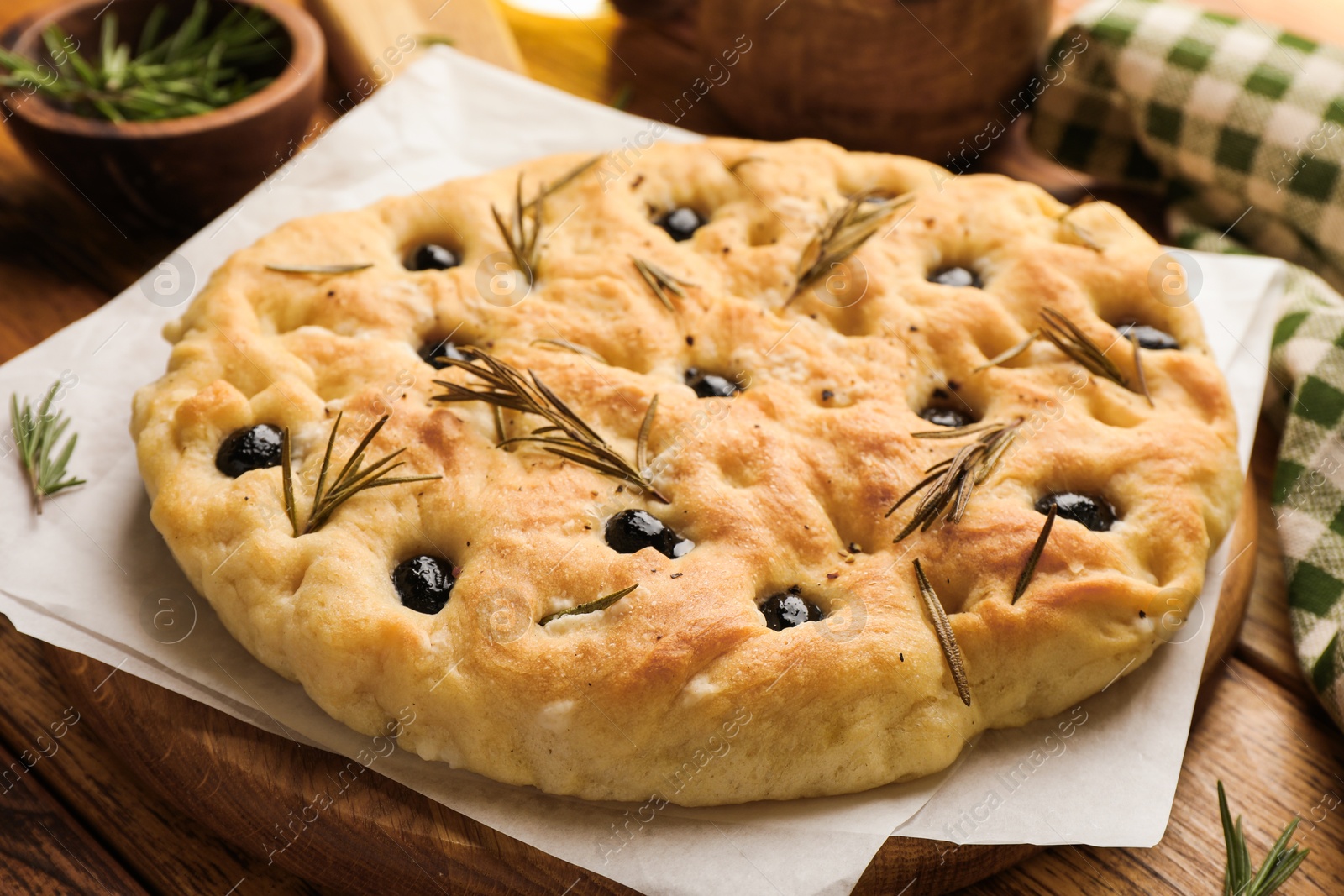 Delicious focaccia bread with olives and rosemary on wooden table, closeup Photo of Delicious focaccia bread with olives and rosemary on wooden table, closeup
