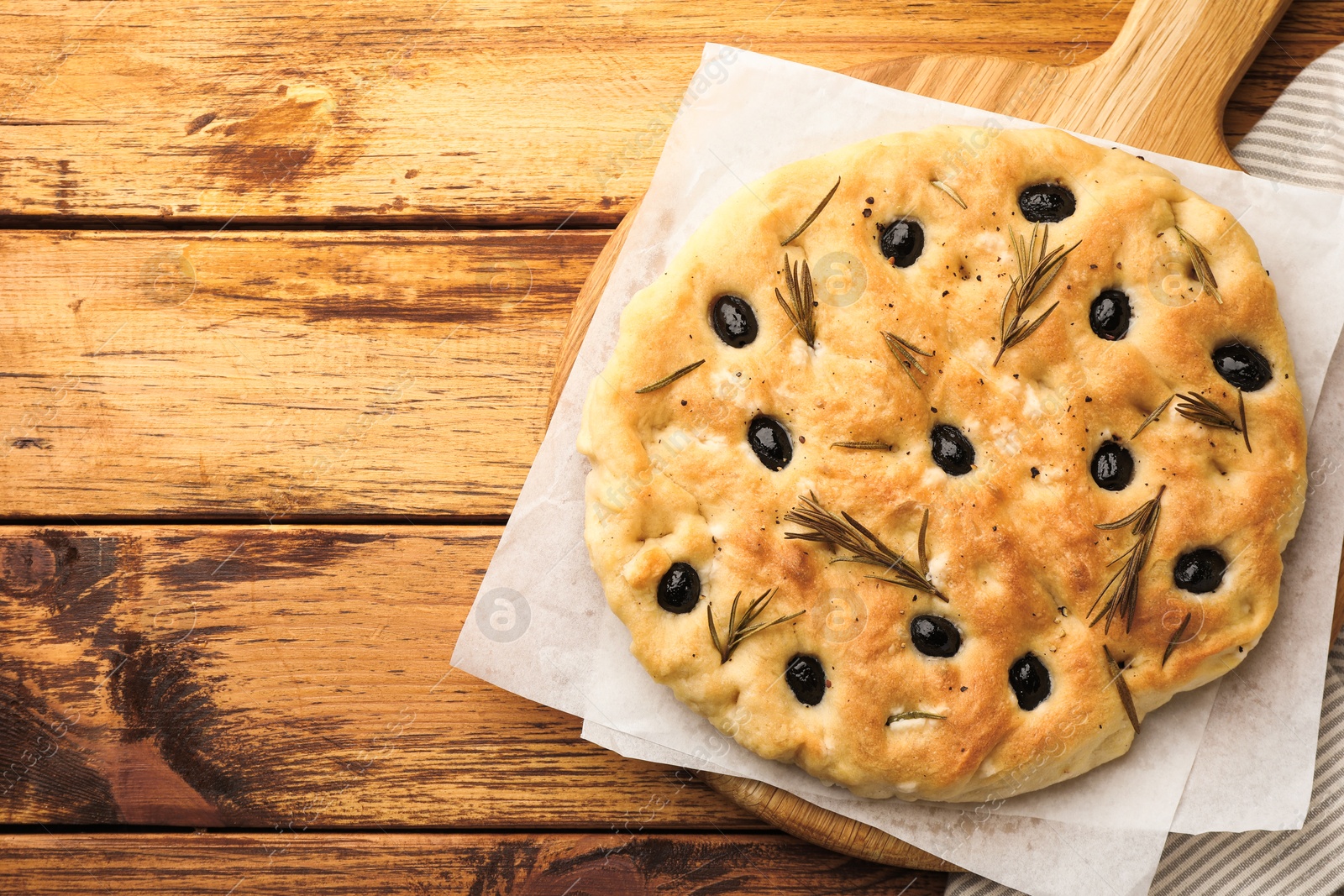Delicious focaccia bread with olives and rosemary on wooden table, top view. Space for text Photo of Delicious focaccia bread with olives and rosemary on wooden table, top view. Space for text