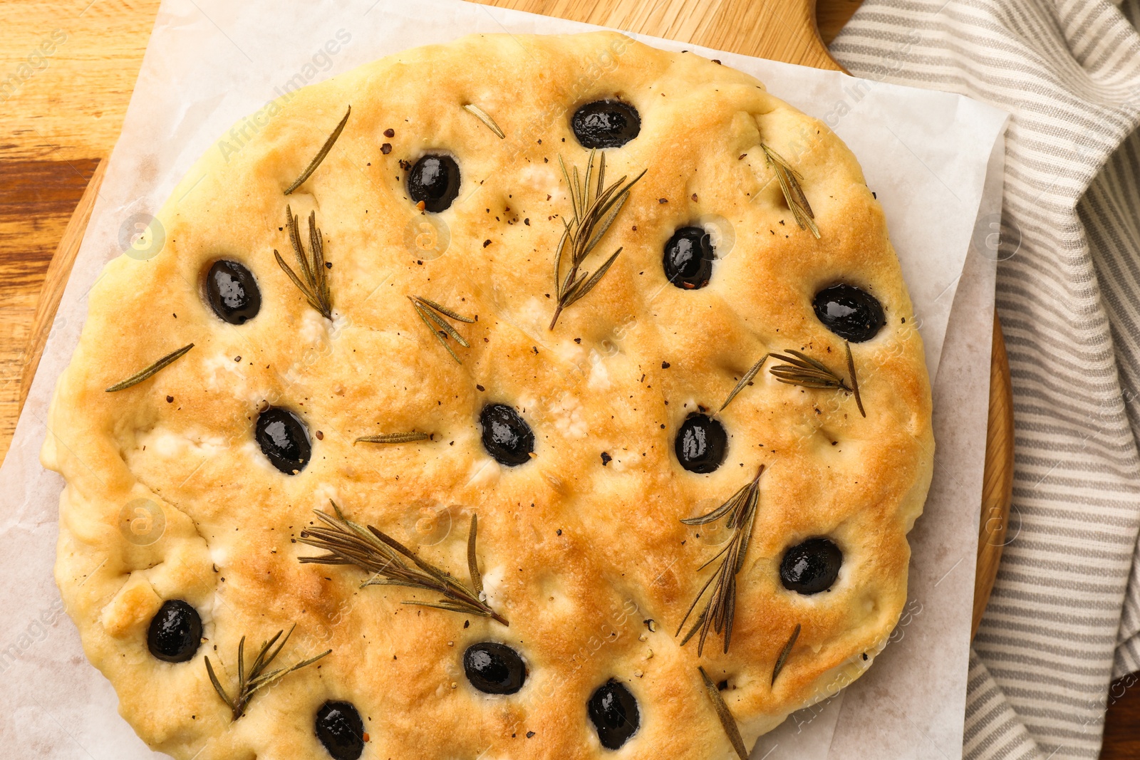 Delicious focaccia bread with olives and rosemary on wooden table, top view Photo of Delicious focaccia bread with olives and rosemary on wooden table, top view