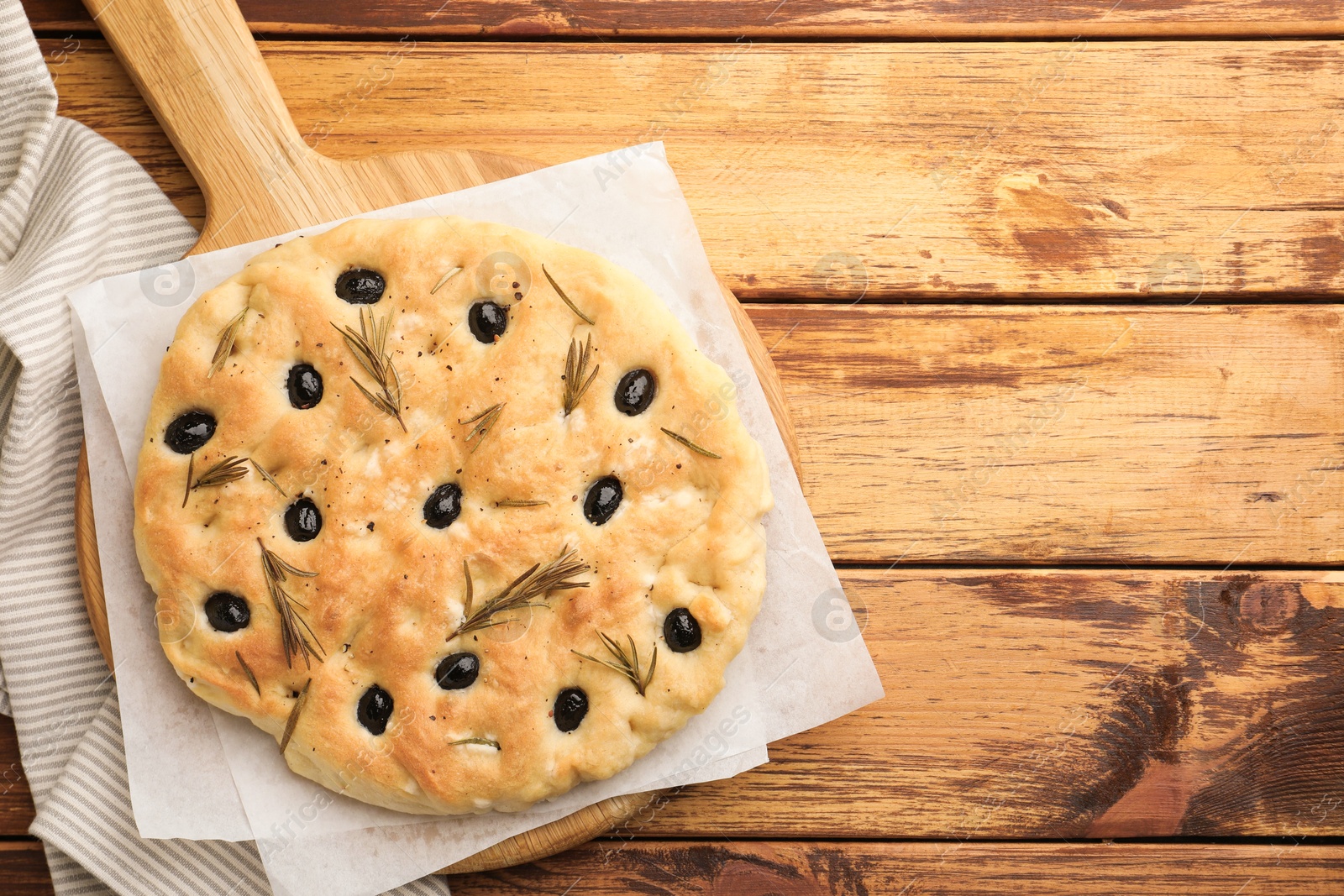 Delicious focaccia bread with olives and rosemary on wooden table, top view. Space for text Photo of Delicious focaccia bread with olives and rosemary on wooden table, top view. Space for text