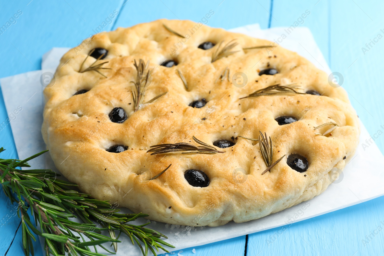 Delicious focaccia bread with olives, rosemary and salt on light blue wooden table, closeup Photo of Delicious focaccia bread with olives, rosemary and salt on light blue wooden table, closeup