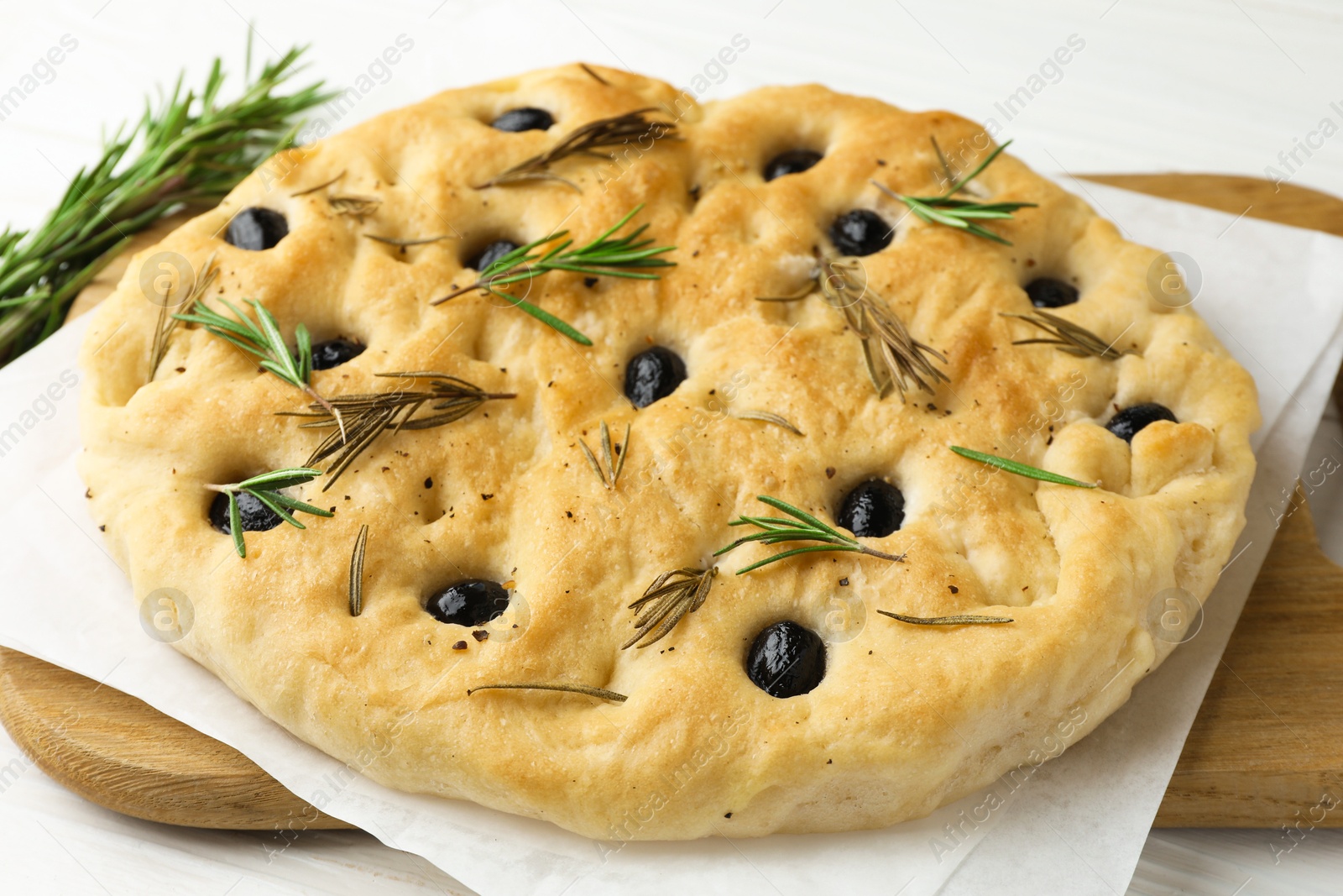 Delicious focaccia bread with olives and rosemary on white wooden table, closeup Photo of Delicious focaccia bread with olives and rosemary on white wooden table, closeup