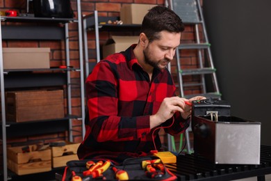 Photo of Relaxing hobby. Man testing deep fryer with multimeter in workshop