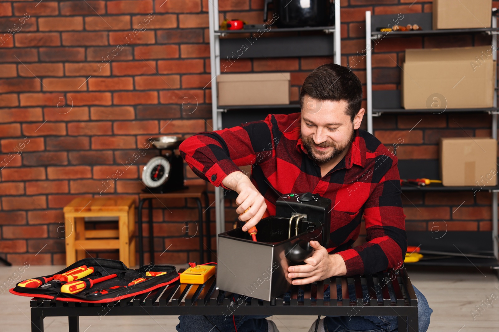 Photo of Relaxing hobby. Man testing deep fryer with multimeter in workshop