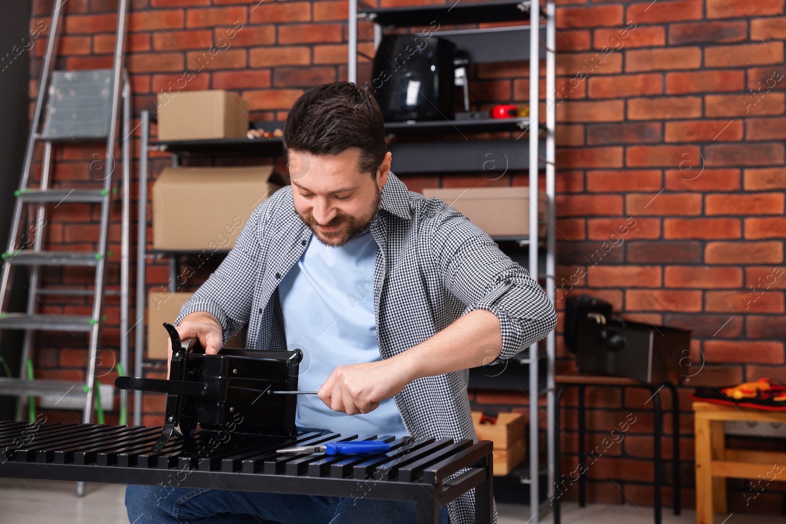 Photo of Relaxing hobby. Man repairing mechanical kitchen scale with screwdriver in workshop