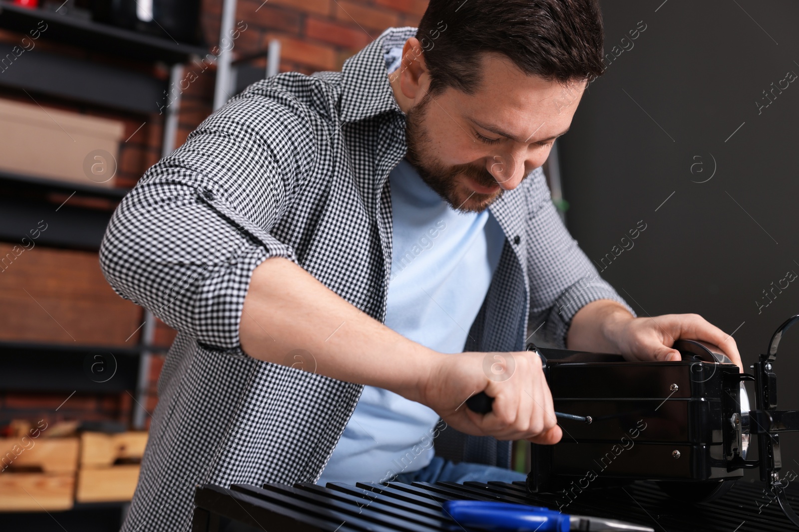 Photo of Relaxing hobby. Man repairing mechanical kitchen scale with screwdriver in workshop