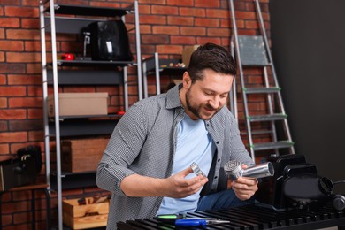 Photo of Relaxing hobby. Man examining parts of electric meat grinder in workshop