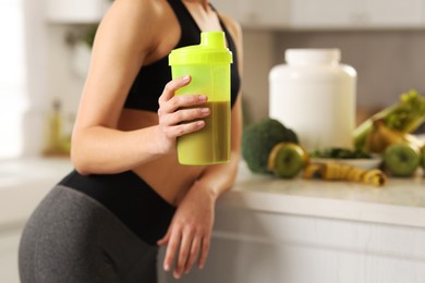 Photo of Weight loss. Woman with shaker of protein in kitchen, closeup