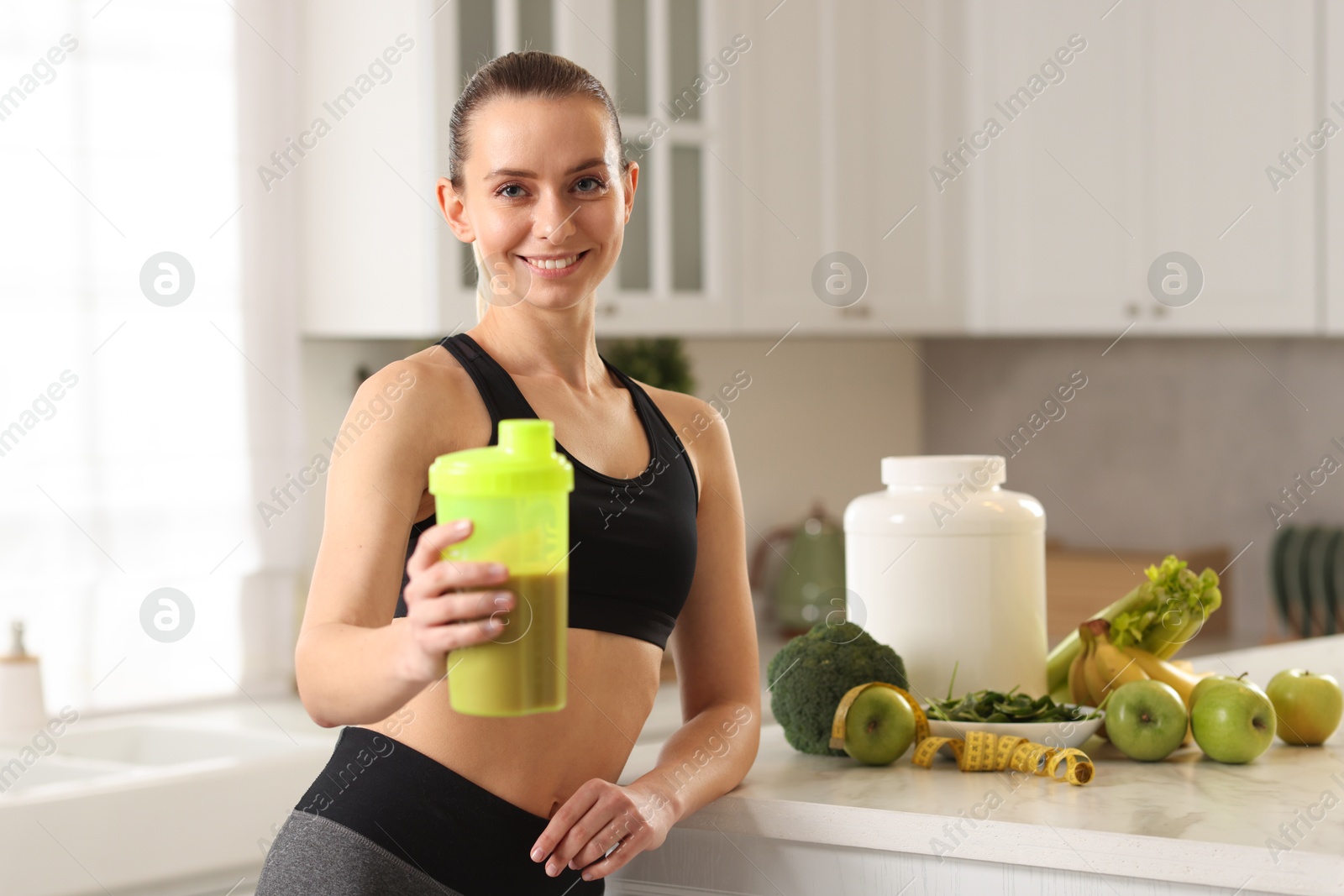 Photo of Weight loss. Happy woman with shaker of protein in kitchen