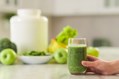 Photo of Weight loss. Woman with glass of healthy shake at white marble table in kitchen, closeup. Space for text