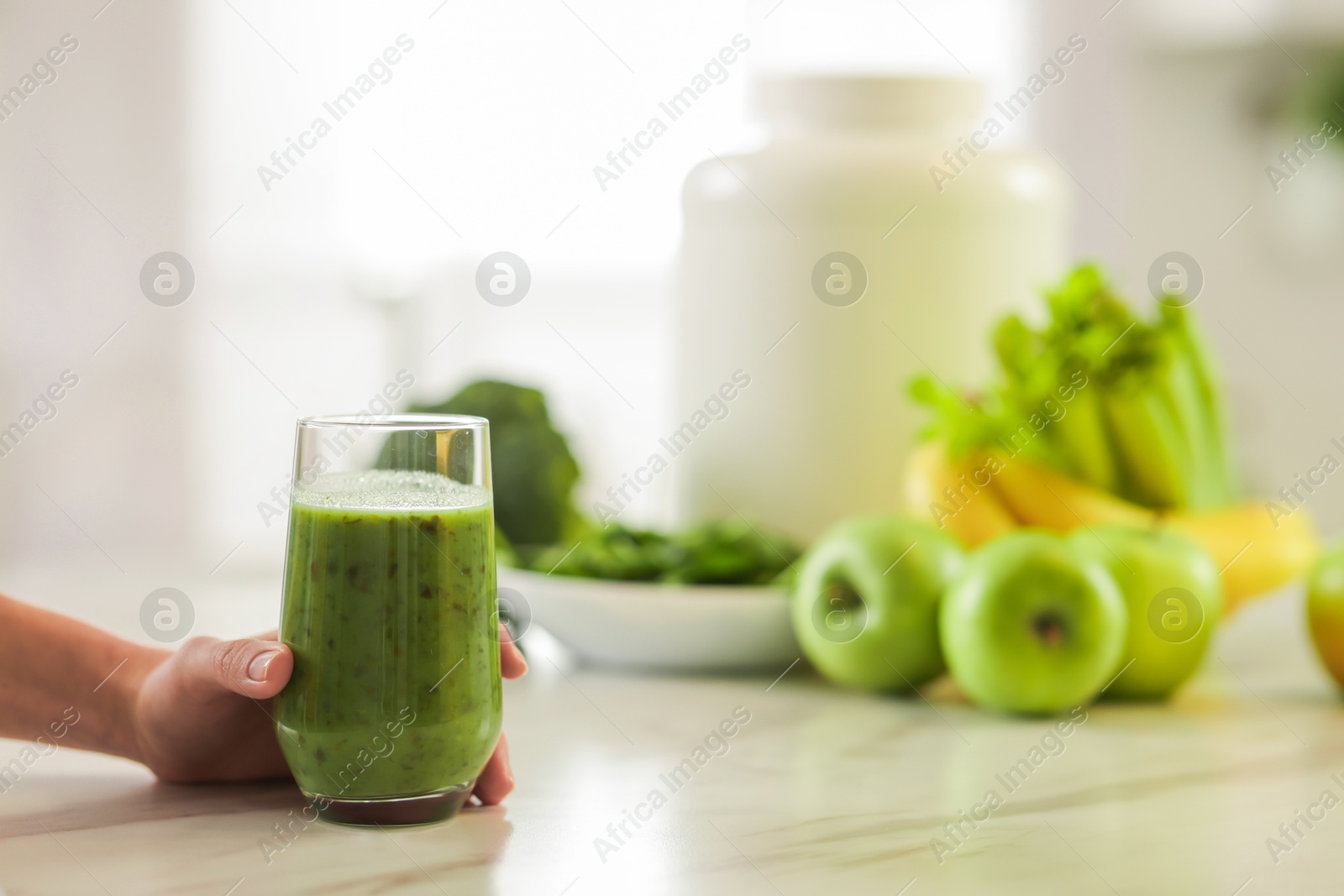 Photo of Weight loss. Woman with glass of healthy shake at white marble table in kitchen, closeup. Space for text