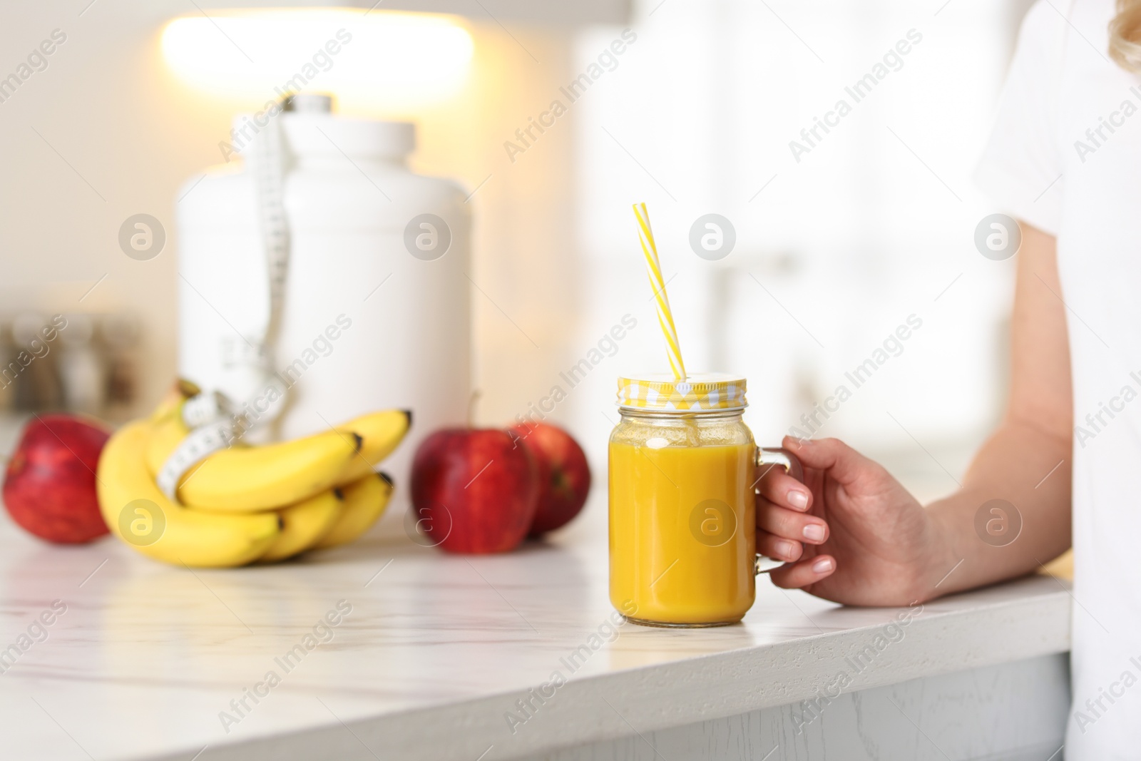 Photo of Weight loss. Woman with tasty shake near white marble table in kitchen, closeup