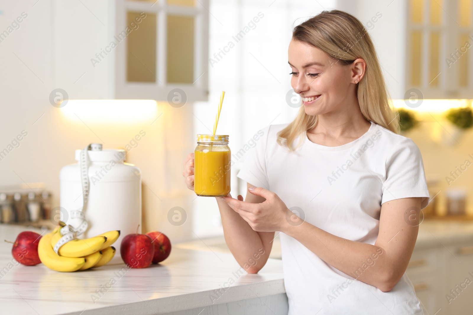 Photo of Weight loss. Woman with tasty shake near white marble table in kitchen