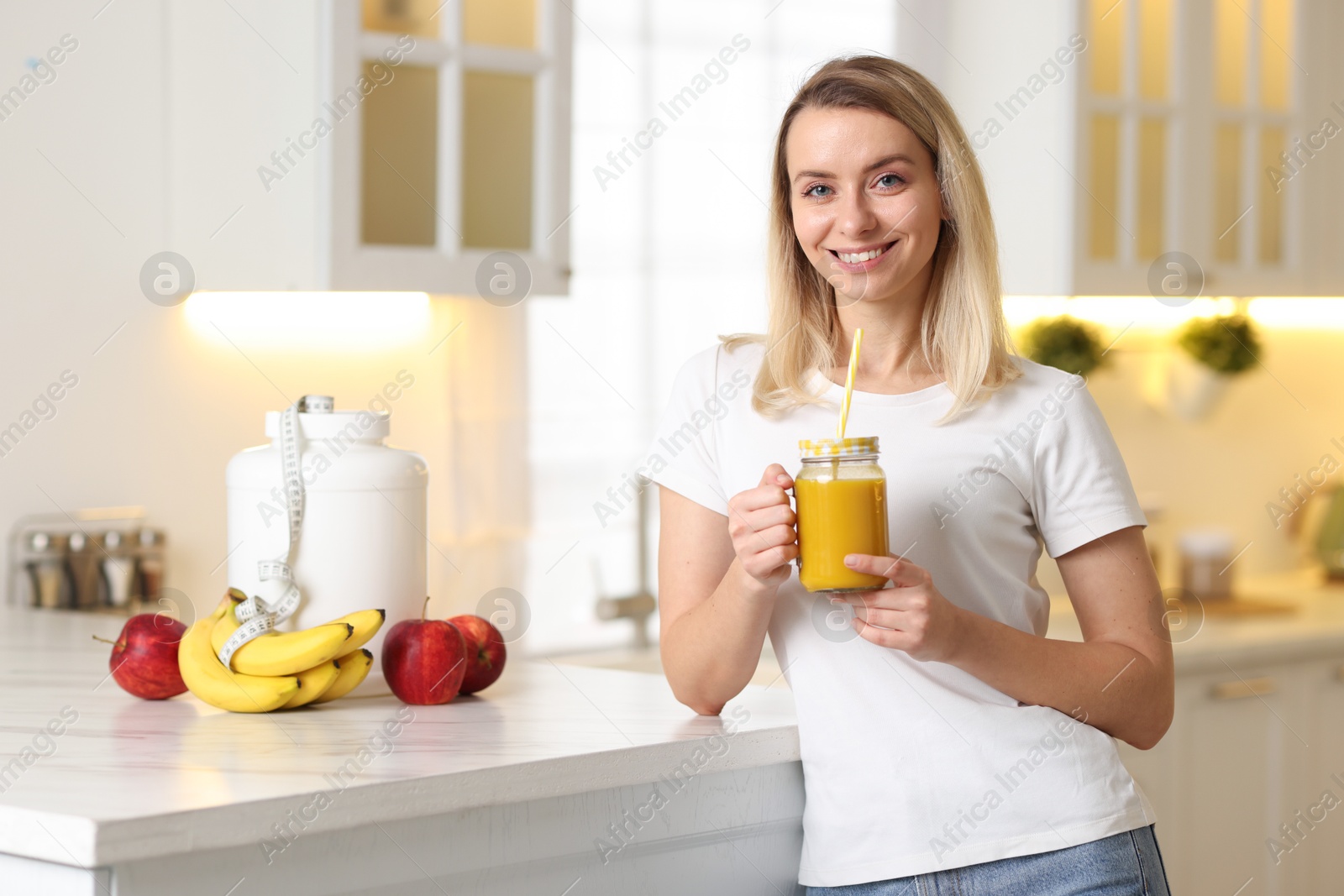 Photo of Weight loss. Woman with tasty shake near white marble table in kitchen