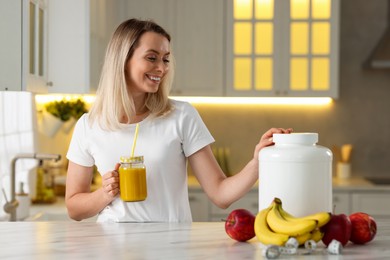 Photo of Weight loss. Happy woman with tasty shake at white marble table in kitchen