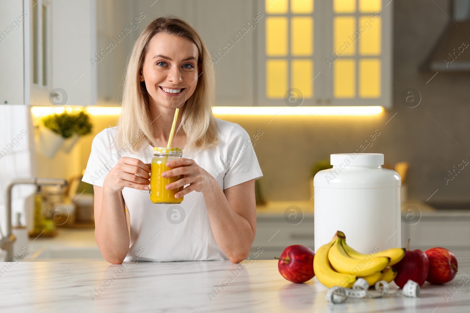 Photo of Weight loss. Happy woman with tasty shake at white marble table in kitchen