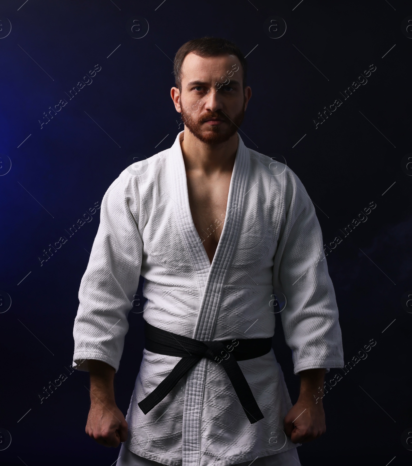 Photo of Man in uniform practicing karate on dark background