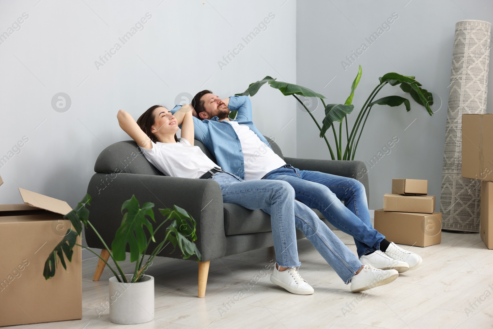 Photo of Moving day. Happy couple resting on couch in their new home