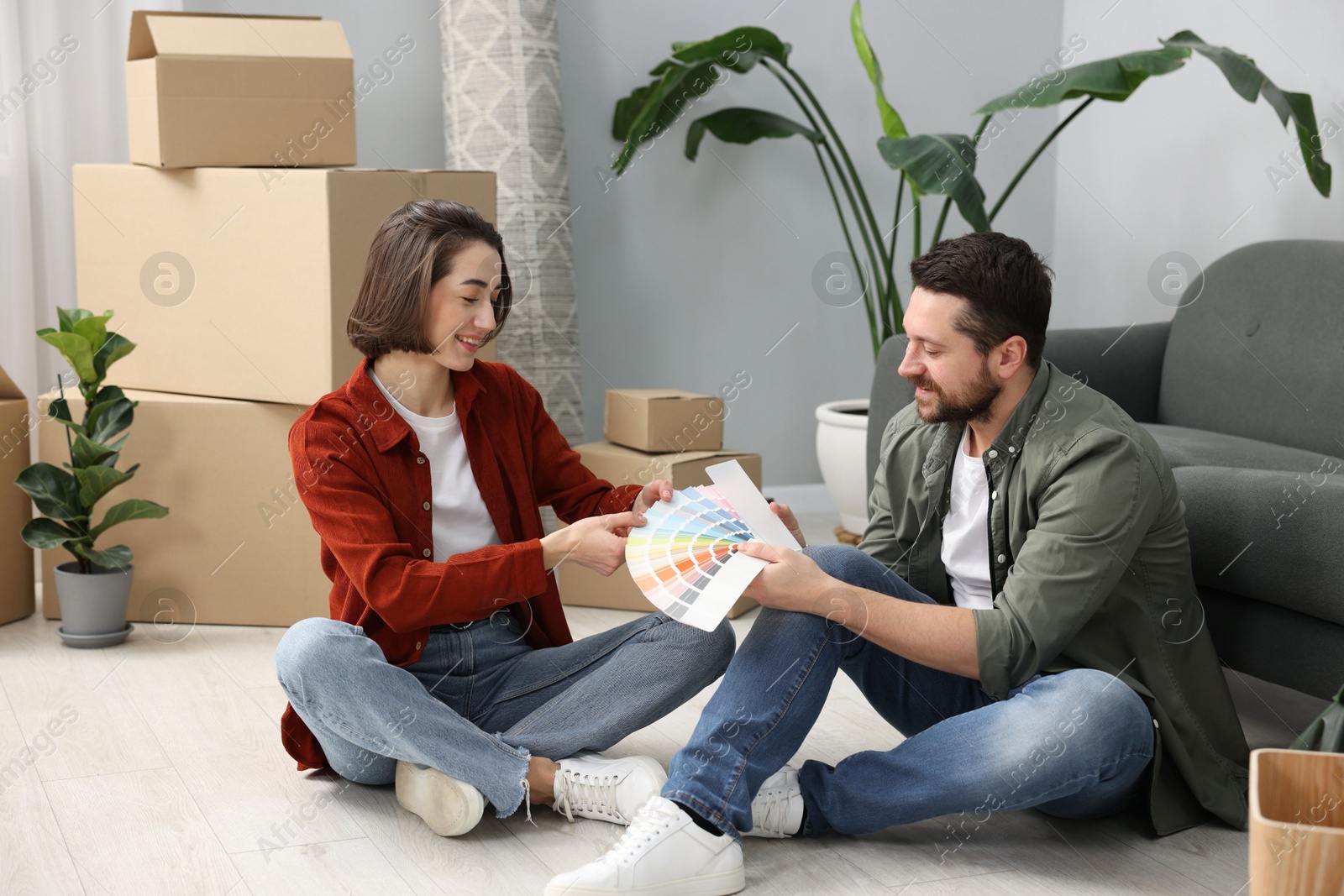 Photo of Moving day. Happy couple choosing paint color for their new home