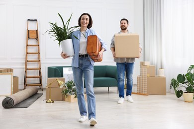 Photo of Moving day. Happy couple with their belongings in new home, selective focus