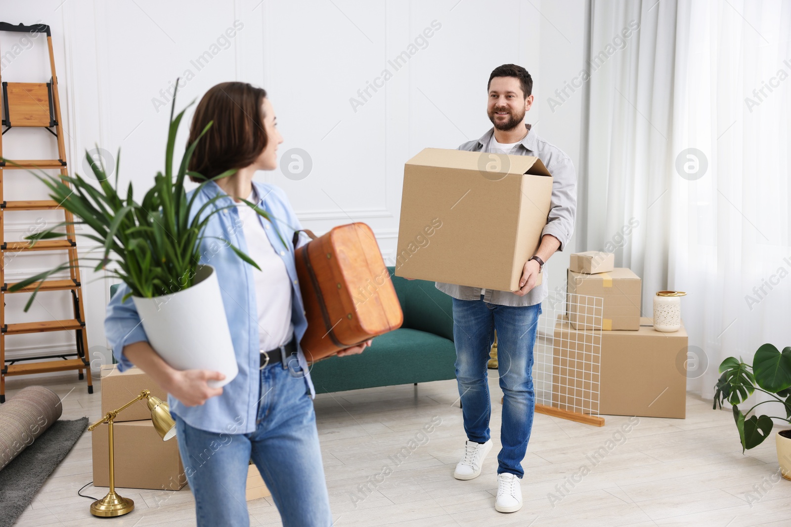 Photo of Moving day. Happy couple with their belongings in new home, selective focus