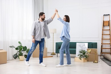 Photo of Moving day. Happy couple dancing in their new home