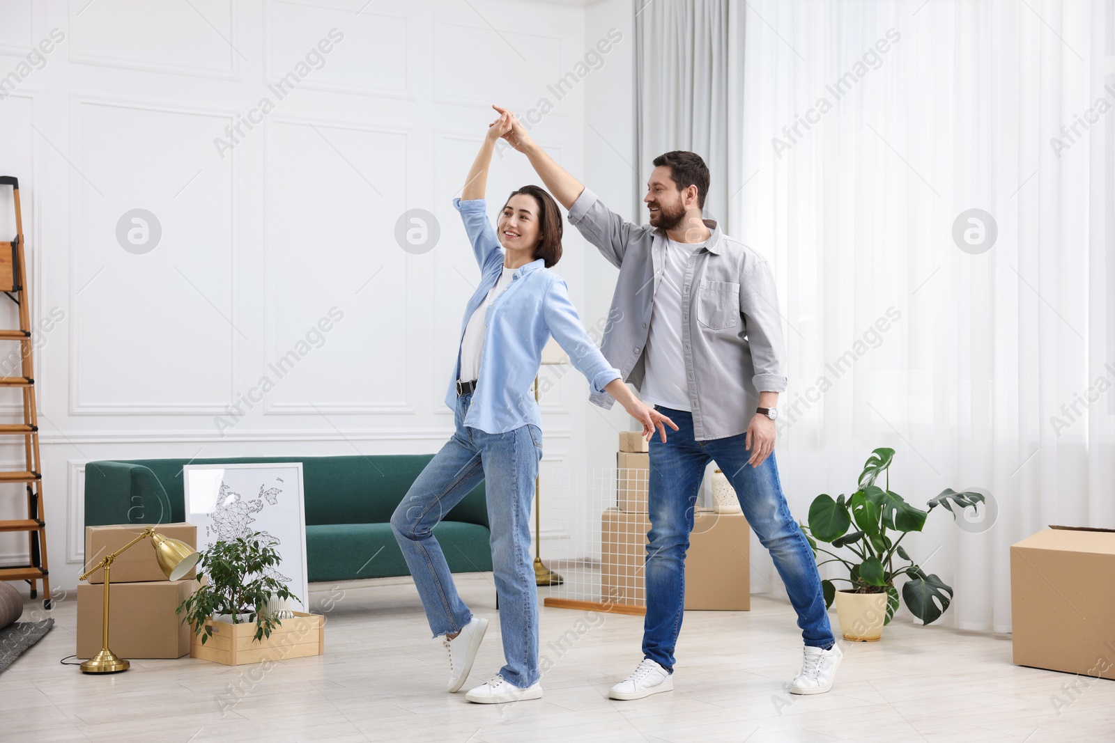 Photo of Moving day. Happy couple dancing in their new home