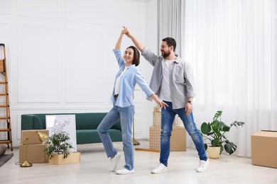 Photo of Moving day. Happy couple dancing in their new home