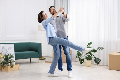 Photo of Moving day. Happy couple dancing in their new home