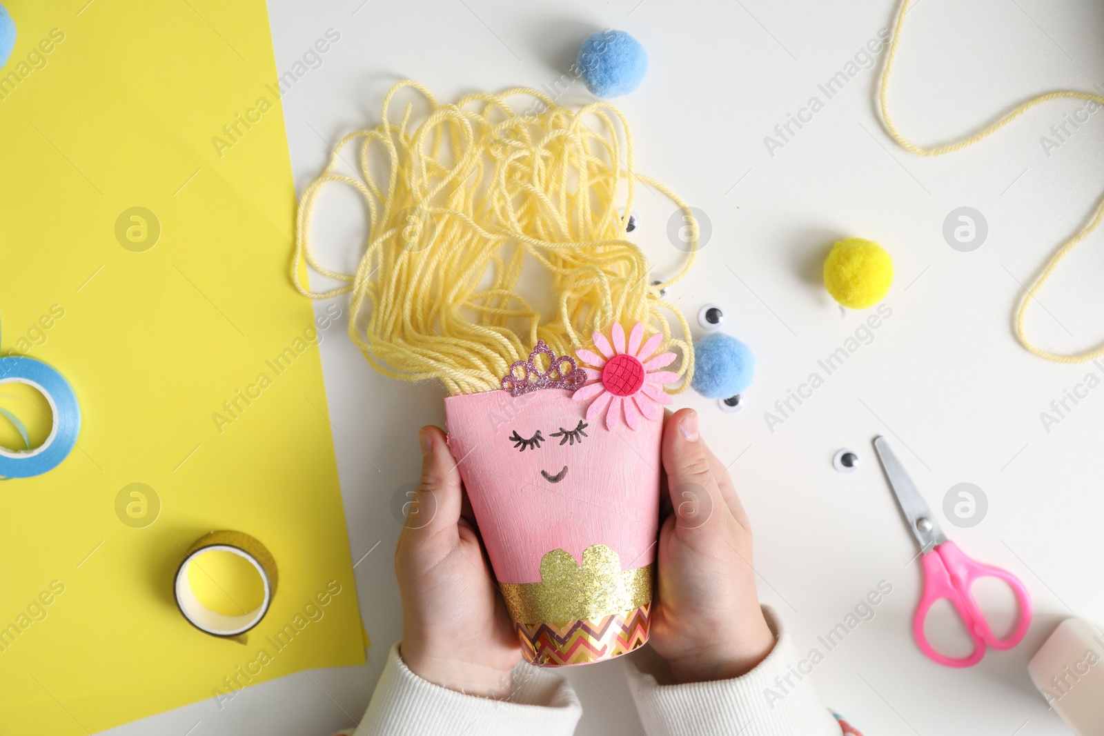 Photo of Little girl with handmade toy at white table, top view. Child creativity and craft