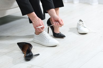 Photo of Woman changing shoes on sofa at home, closeup