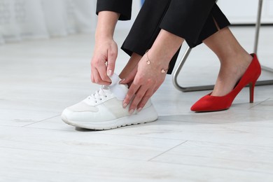 Photo of Woman changing shoes on chair at home, closeup